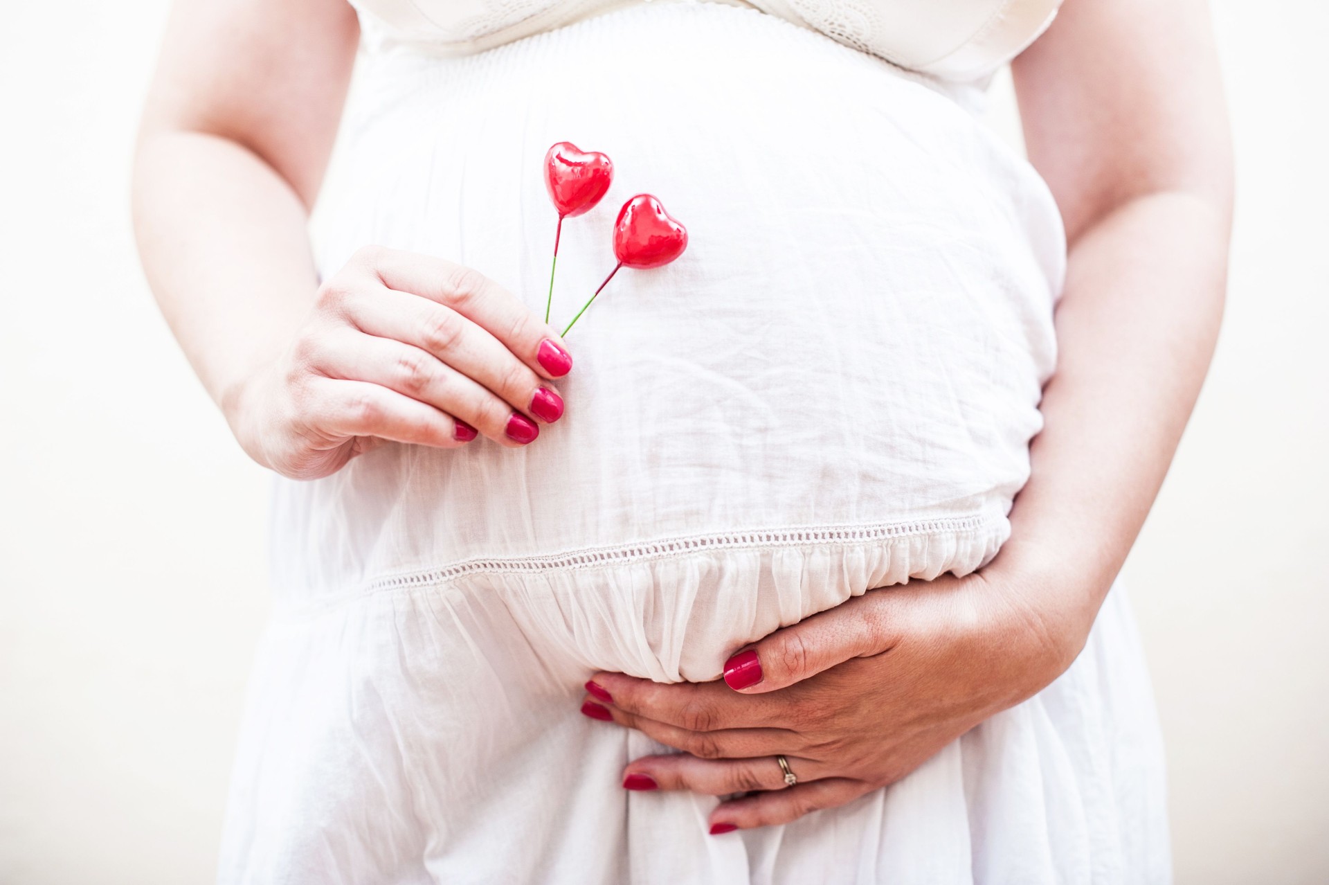 Pregnant Woman Holding Two Red Hearts in Her Hand